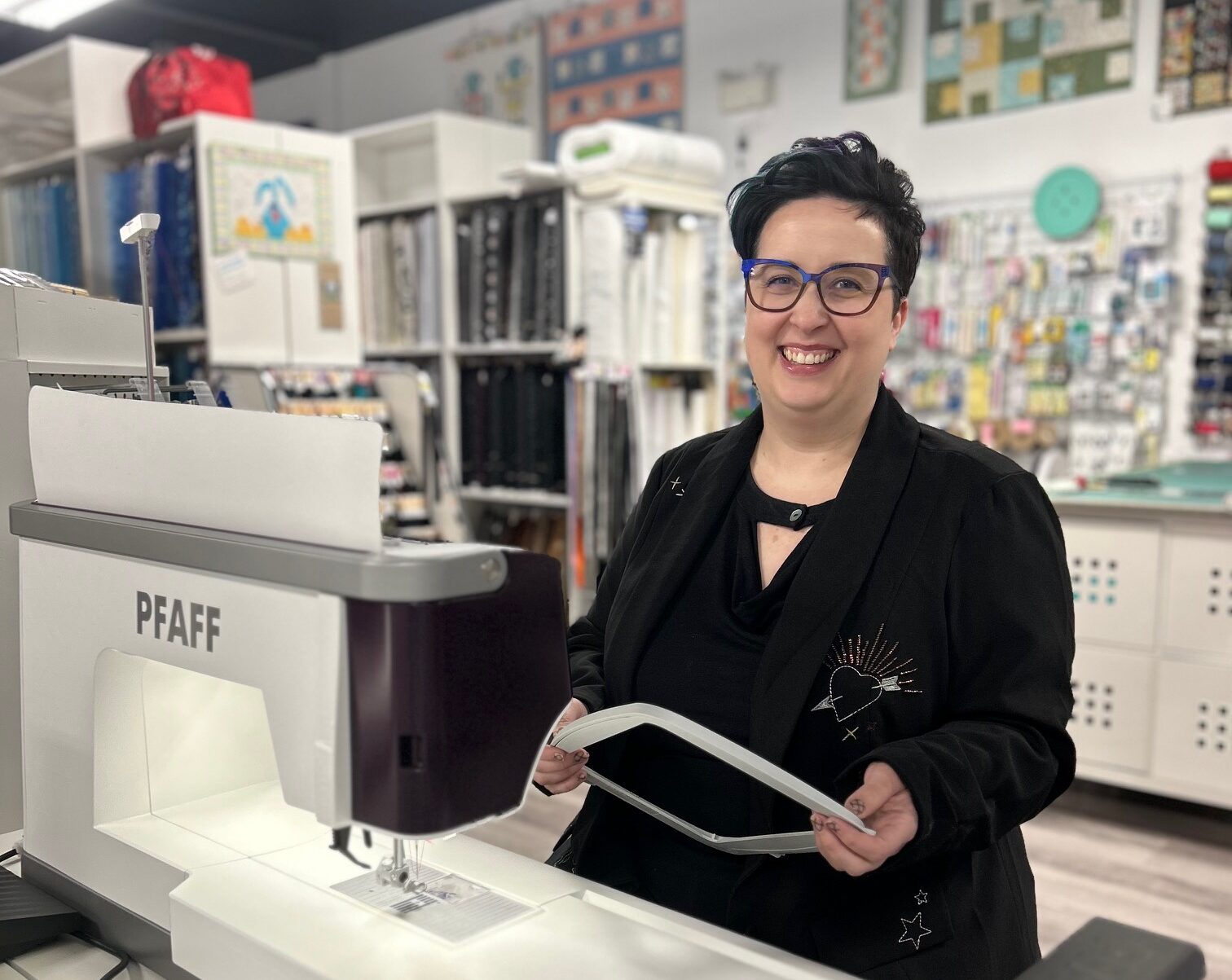 Embellish business owner smiles behind sewing machine